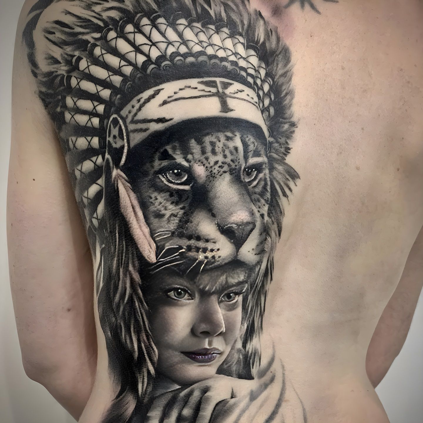 Tatuaje realista de niña con tocado indio y leopardo realizado por Aitor Murga en Ink for All