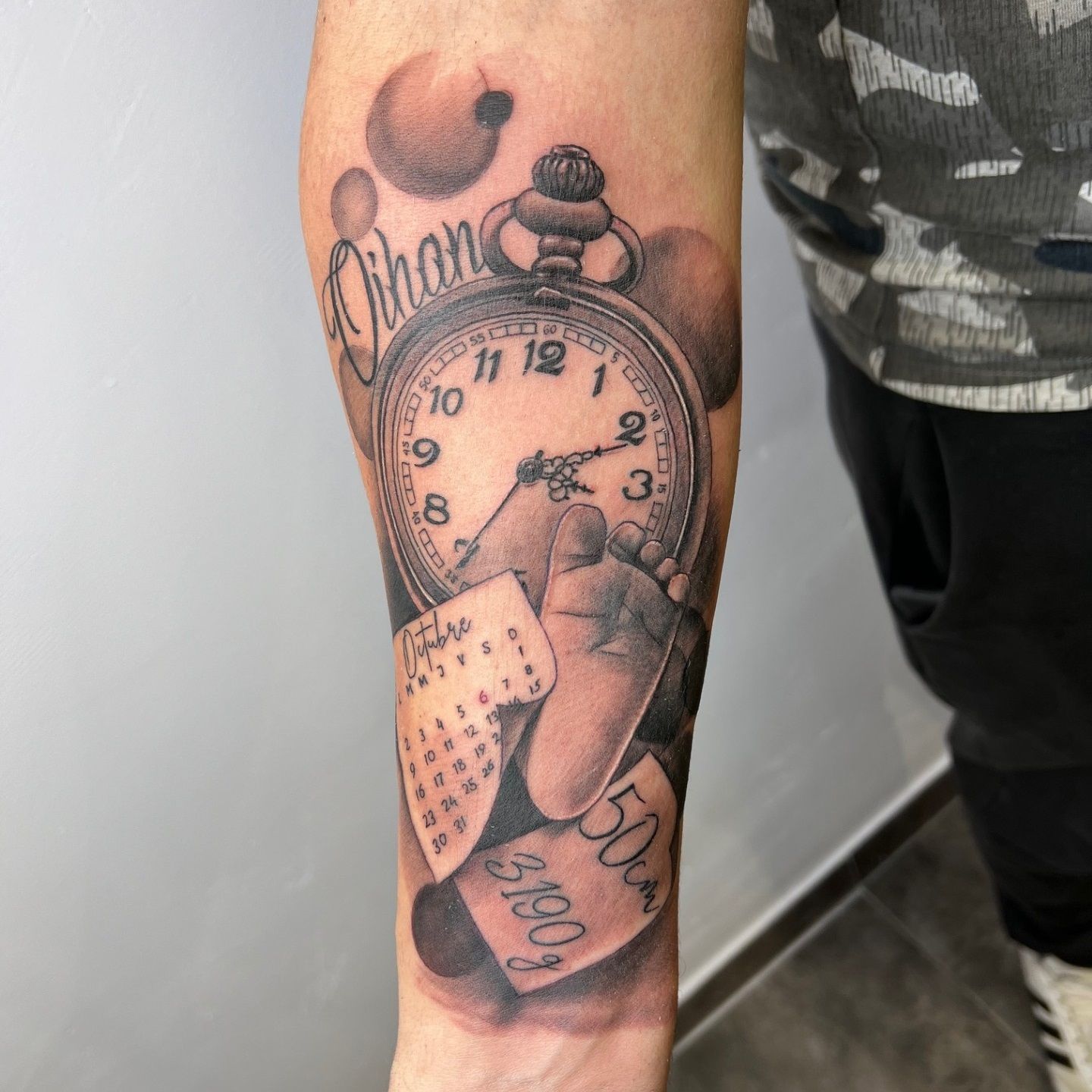 Tattoo de reloj, calendario y pie de bebe realizado por Aitor Murga en Ink for All